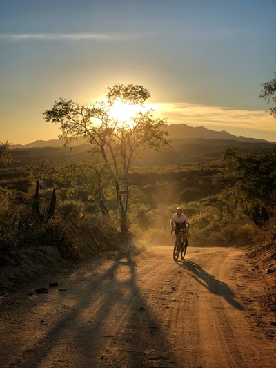 Man in black jacket during the day on the road to ride a bicycle
